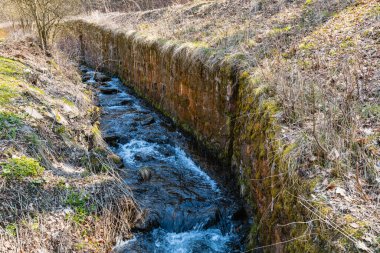 Nehrin yanındaki yüksek duvarlı dağ yolunun yanındaki uzun dere.
