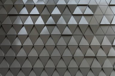 Parlak çelik üçgenlerle dolu bir bina duvarı.