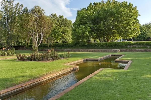 Fragment of rosarium with pond in Botanical Garden — Stock Photo, Image