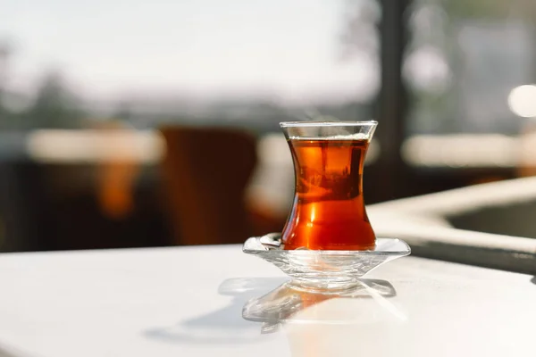 Turkish tea served in tulip-shaped glass on rustic table. Turkish tea in traditional glass cup.