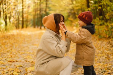 Anne ve oğlu sonbahar ormanında yürüyorlar. Çocuklu aile için sonbahar açık hava aktivitesi