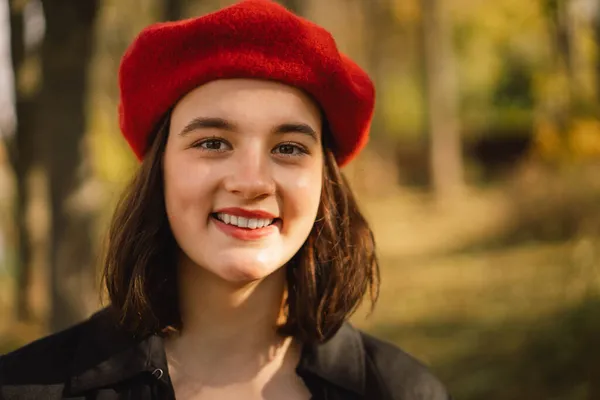 Seorang Teengirl dengan baret merah dengan buket daun musim gugur di tangannya berjalan melalui hutan — Stok Foto