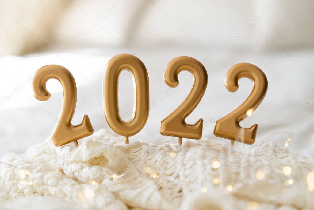 Happy New Years 2022. Christmas background with 2022 candles and white knit sweater.