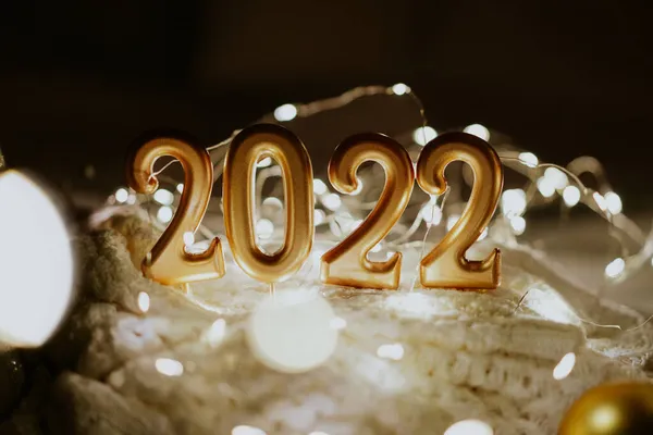 สุขสันต์วันปีใหม่ 2022. หมายเลข 2022 ทําโดยเทียนบนพื้นหลัง bokeh เทศกาลส่องแสงในความมืด — ภาพถ่ายสต็อก