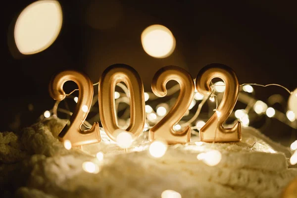 Feliz Año Nuevo 2022. Número 2022 hecho por las velas en un festivo brillante fondo bokeh en la oscuridad — Foto de Stock