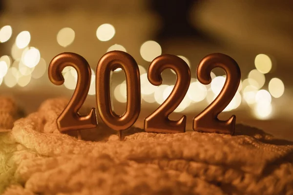 สุขสันต์วันปีใหม่ 2022. หมายเลข 2022 ทําโดยเทียนบนพื้นหลัง bokeh เทศกาลส่องแสงในความมืด — ภาพถ่ายสต็อก