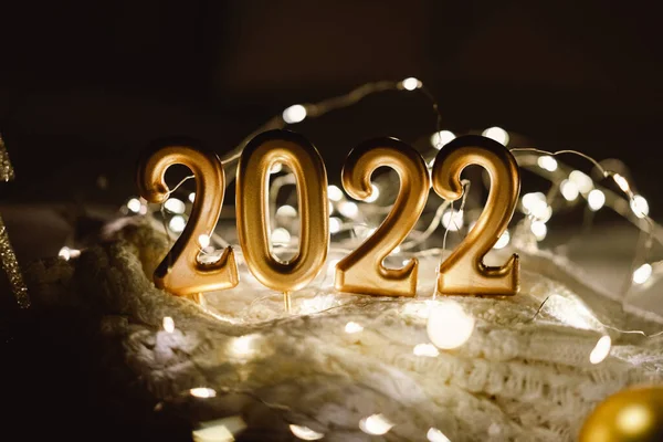 สุขสันต์วันปีใหม่ 2022. หมายเลข 2022 ทําโดยเทียนบนพื้นหลัง bokeh เทศกาลส่องแสงในความมืด — ภาพถ่ายสต็อก