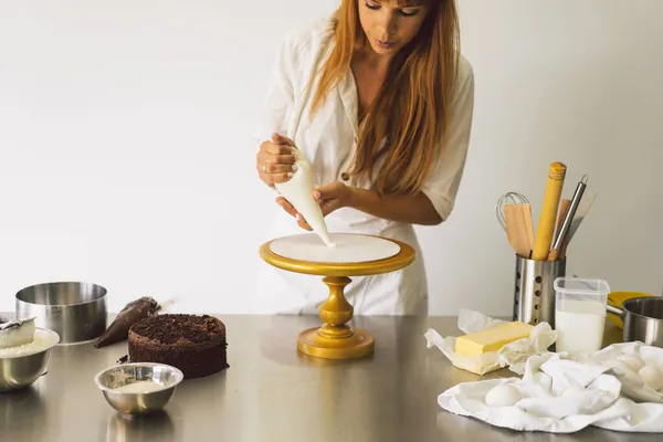 Дівчина-кондитер готує торт з білим кремом і шоколадом. Приготування тортів . — стокове фото