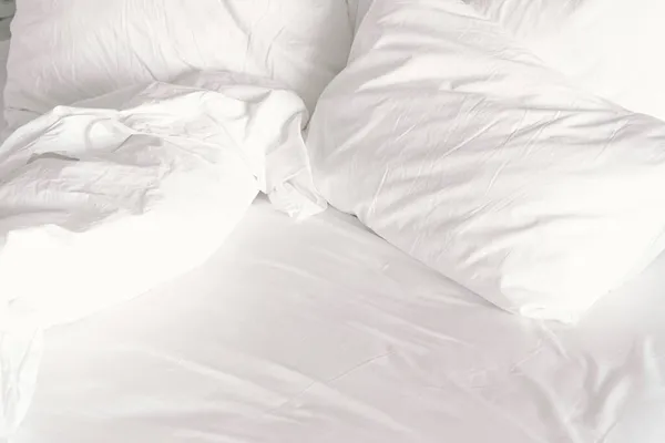 Λευκό άνετο κρεβάτι και μαλακό μαξιλάρι στο υπνοδωμάτιο. Λευκή κουβέρτα στο υπνοδωμάτιο του ξενοδοχείου. — Φωτογραφία Αρχείου