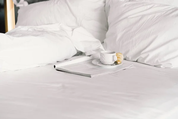 Otel odasındaki yatağın üstünde kahvaltı. Kar beyazı bir yatakta kahvaltı, kruvasanla kahve. — Stok fotoğraf