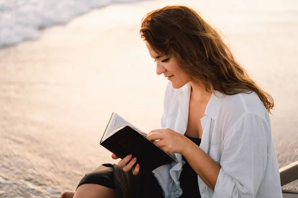 Christelijke vrouw houdt bijbel in haar handen. Het lezen van de Bijbel op zee tijdens de prachtige zonsondergang — Stockfoto