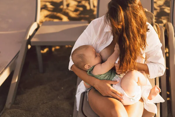 Yeni doğmuş erkek bebek sahilde annesinin göğüslerinden süt emiyor..