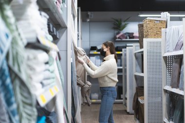 Mağazada yüz maskesi ve koruyucu eldiven takan genç bir kadın var. Günümüzde insanlar yaşam tarzı konsepti