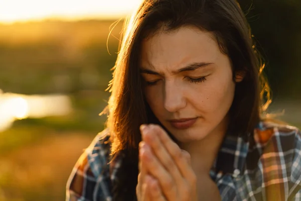 Wanita menutup matanya, berdoa di lapangan selama matahari terbenam yang indah. — Stok Foto