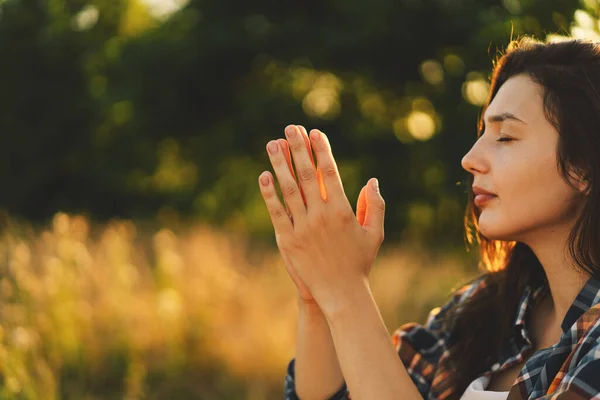 La mujer cerró los ojos, rezando en un campo durante el hermoso atardecer. —  Fotos de Stock