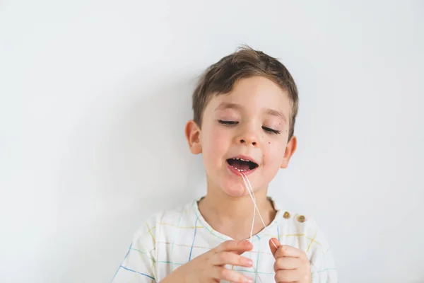 Anak manis menarik gigi longgar menggunakan benang gigi. Proses untuk menghapus gigi bayi. — Stok Foto
