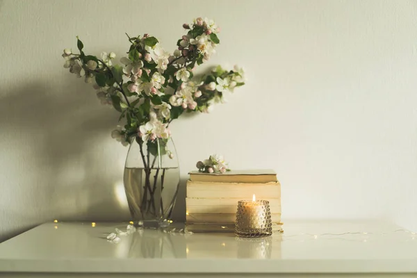 Livre, bougie et vase avec des fleurs de printemps de pomme. — Photo