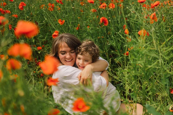 Feliz Día de las Madres. Niño y madre están jugando en un hermoso campo de amapolas rojas — Foto de Stock