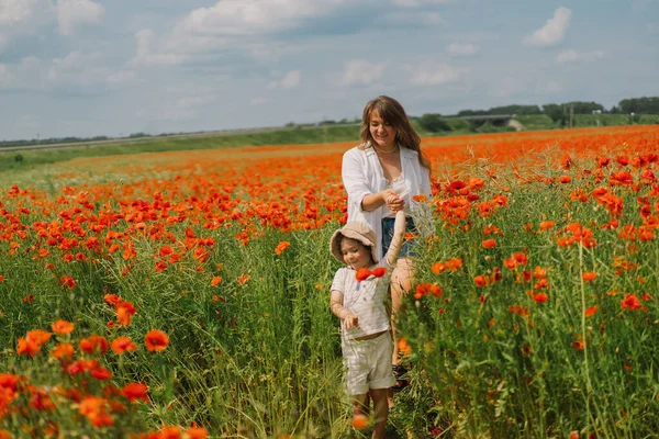 Šťastný Den matek. Malý chlapec a matka hraje v krásném poli červených máků — Stock fotografie