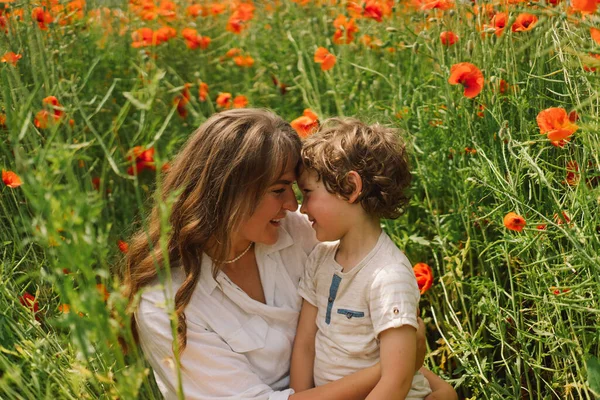 Feliz Día de las Madres. Niño y madre están jugando en un hermoso campo de amapolas rojas — Foto de Stock