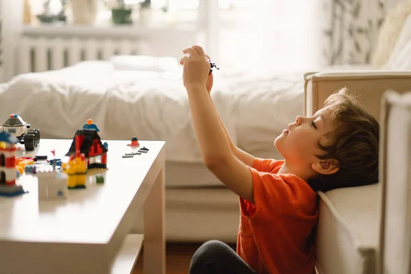 Aranyos fiú építőmunkást játszik otthon. Gyerekjáték otthon a gyerekszobában.. — Stock Fotó