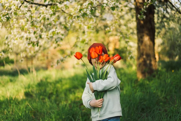Niño feliz alegre con tulipanes ramo de flores en la naturaleza. — Foto de Stock