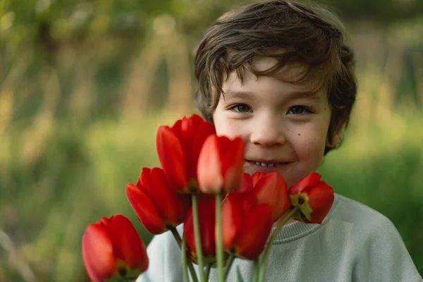 Niño feliz alegre con tulipanes ramo de flores en la naturaleza. —  Fotos de Stock