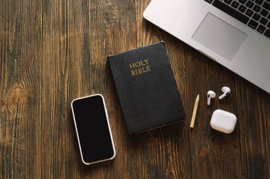 Pazar günü kilise online yeni normal konsept. İncil, cep telefonu ve ahşap bir arka planda kulaklık..
