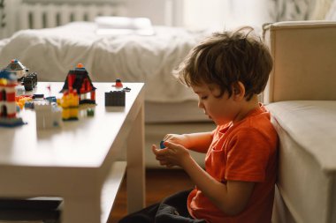 Şirin çocuk evde inşaatçılık oynuyor. Çocuk evde oyuncaklarla oynuyor..