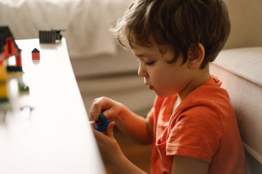 Şirin çocuk evde inşaatçılık oynuyor. Çocuk evde oyuncaklarla oynuyor..