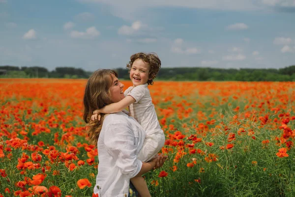 Buona festa della mamma. Bambino e madre sta giocando in un bellissimo campo di papaveri rossi — Foto Stock