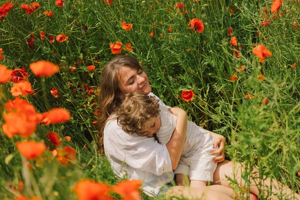 Feliz Dia das Mães. Menino e mãe está brincando em um belo campo de papoilas vermelhas — Fotografia de Stock