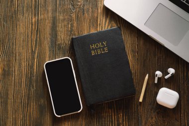 Pazar günü kilise online yeni normal konsept. İncil, cep telefonu ve ahşap bir arka planda kulaklık..