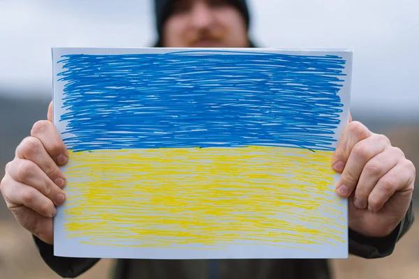 Ουκρανός κρατά μια ζωγραφισμένη σημαία της Ουκρανίας. Πόλεμος της Ρωσίας κατά της Ουκρανίας. — Φωτογραφία Αρχείου