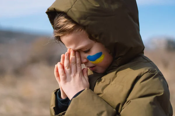 Український хлопчик заплющив очі і молився, щоб зупинити війну в Україні. — стокове фото