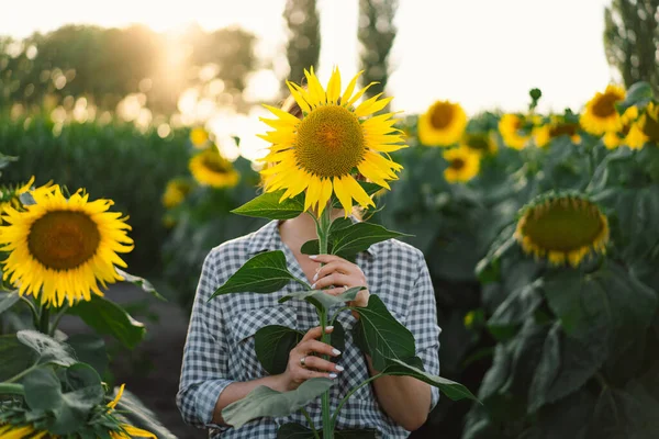Beautiful young woman with sunflowers enjoying nature and laughing on summer sunflower field.