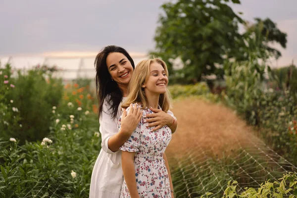 Eine junge Mutter mit einer halbwüchsigen Tochter verbringt Zeit im Garten. Familienurlaub und Zweisamkeit. — Stockfoto