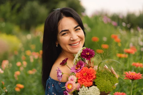 Uma jovem caminha com um buquê de flores em uma fazenda de flores florística. — Fotografia de Stock