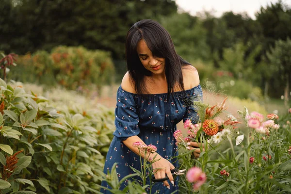 A Young woman prune flowers in a floristic flower farm. Woman florist. — Stock Photo, Image