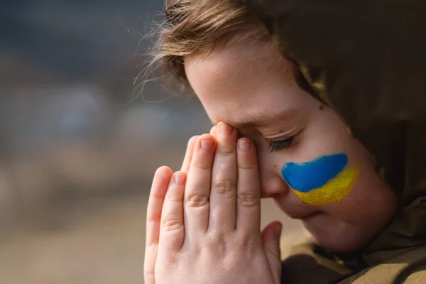Ουκρανό αγόρι έκλεισε τα μάτια της και προσεύχεται να σταματήσει τον πόλεμο στην Ουκρανία. — Φωτογραφία Αρχείου