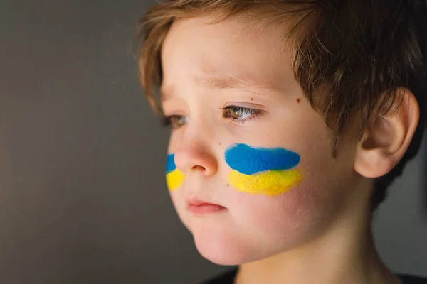 รูปภาพของเด็กชายยูเครนที่มีใบหน้าวาดด้วยสีของธงยูเครน . — ภาพถ่ายสต็อก