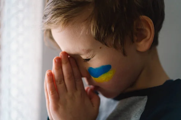 Menino ucraniano fechou os olhos e orando para parar a guerra na Ucrânia. — Fotografia de Stock