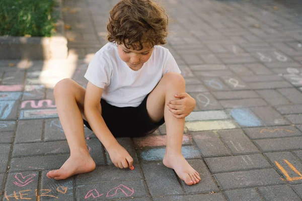 Pequeño niño preescolar dibuja con tiza de colores en el suelo. —  Fotos de Stock