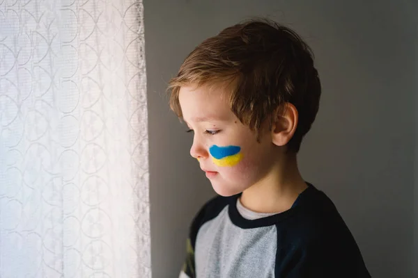 Retrato de un niño ucraniano con una cara pintada con los colores de la bandera ucraniana. —  Fotos de Stock