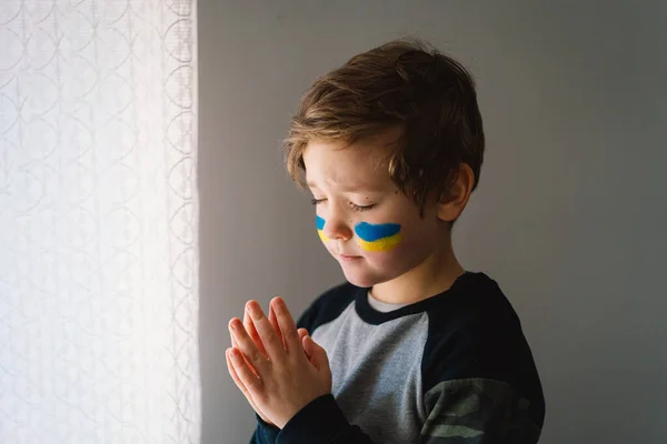เด็กชายยูเครนปิดตาของเธอและอธิษฐานเพื่อหยุดสงครามในยูเครน . — ภาพถ่ายสต็อก