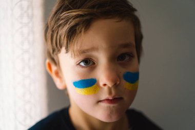 Ukrayna bayrağının renkleriyle boyanmış yüzü olan Ukraynalı bir çocuğun portresi.