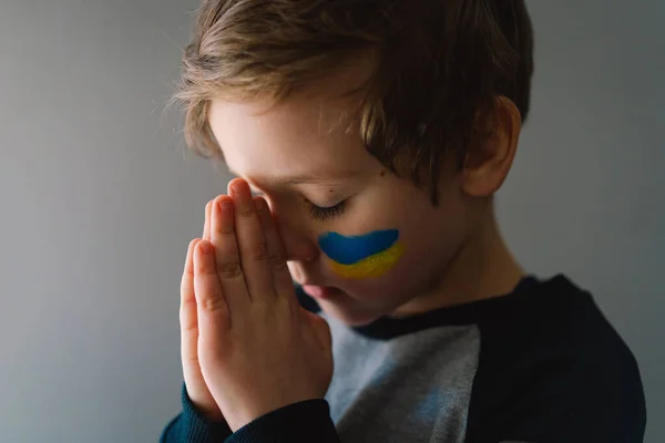 ウクライナの少年は彼女の目を閉じて、ウクライナでの戦争を停止するために祈る. — ストック写真