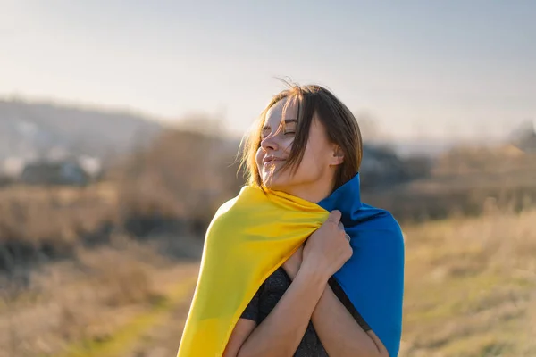 Жінка тримає жовтий і синій прапор України на відкритому повітрі. — стокове фото