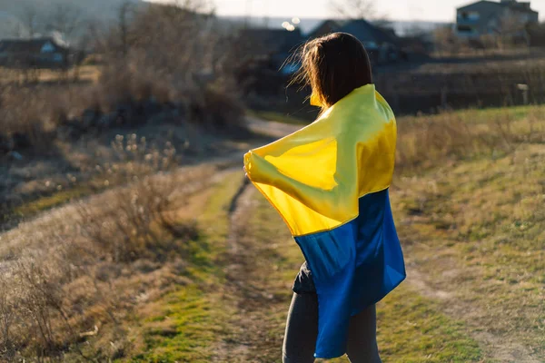 Жінка тримає жовтий і синій прапор України на відкритому повітрі. — стокове фото