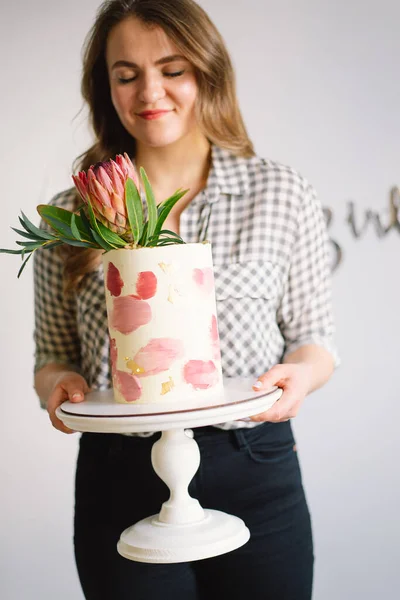 Wanita muda dengan kue ulang tahun, tutup. Kue ini dihiasi dengan bunga protea. — Stok Foto